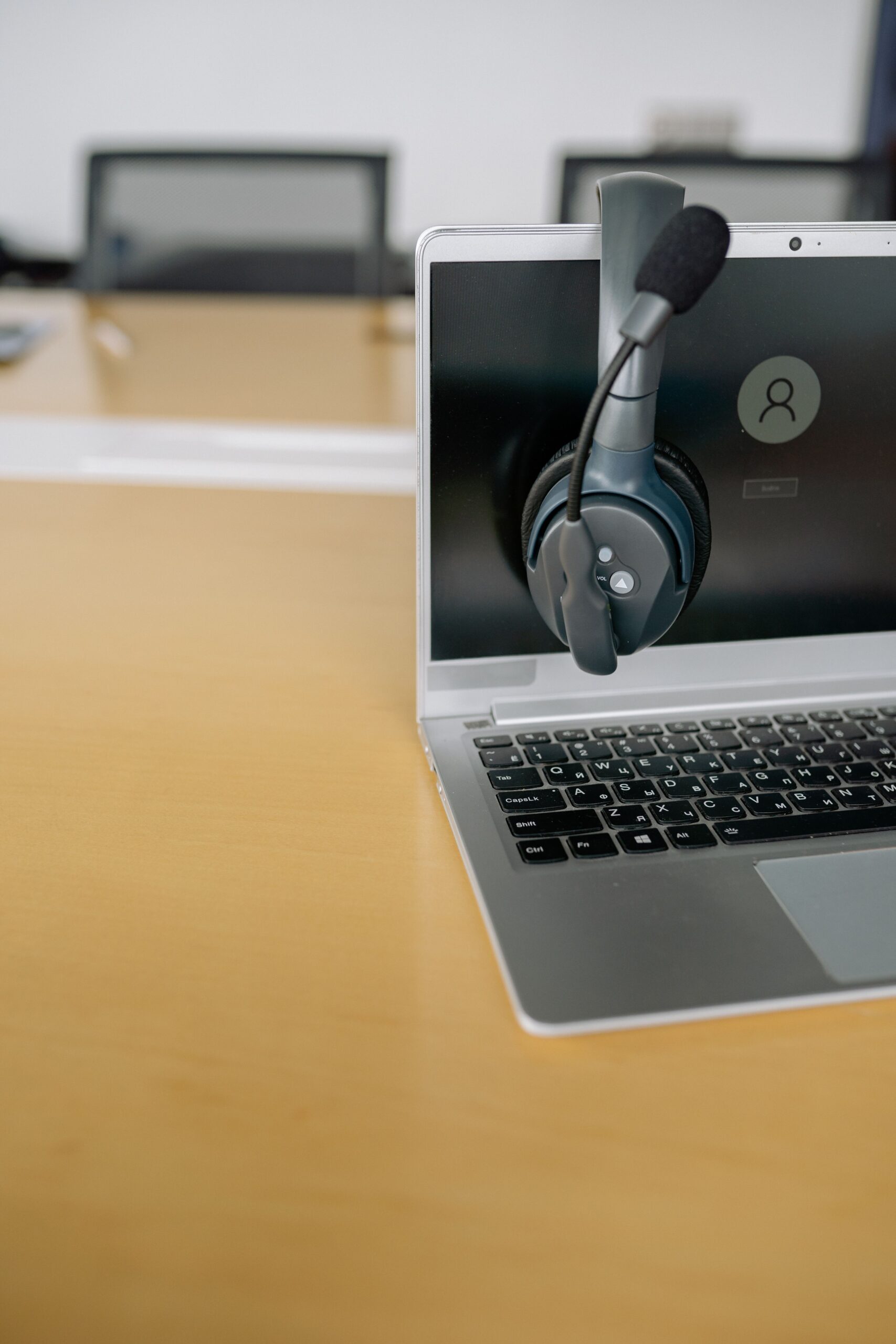 Laptop with headset on a conference table, ideal for remote work imagery.